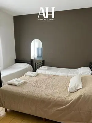 two beds in a bedroom with a sign on the wall at American Hoteles in Villa Carlos Paz