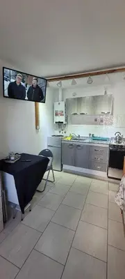 a kitchen with a table and a tv on the wall at Balcones del Cerro Mono ambiente céntrico 2p - camas simples in Villa Carlos Paz