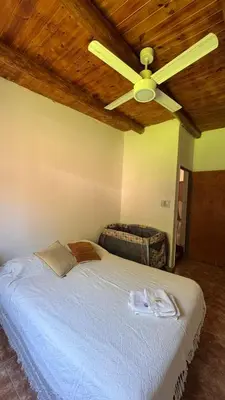 a bedroom with a white bed with a ceiling fan at LA FACUNDA in San Francisco del Monte de Oro