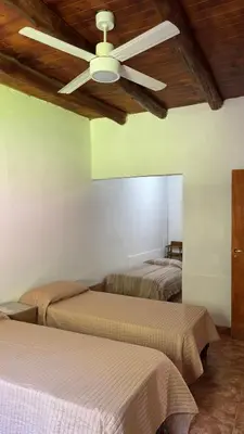 two beds in a room with a ceiling fan at LA FACUNDA in San Francisco del Monte de Oro