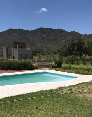 a swimming pool in a field with a mountain in the background at La Americana, casa entre sierras in Luján