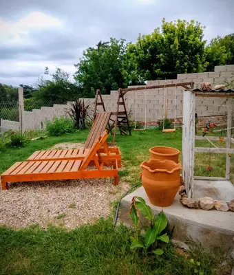 a wooden bench sitting in a yard with a pot at ENCANTO SERRANO in Villa Carlos Paz