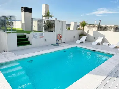 a swimming pool with chairs next to a building at HABITAT Departamentos in Villa Carlos Paz