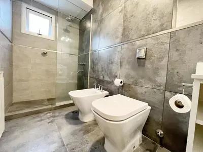 a bathroom with a toilet and a sink and a window at HABITAT Departamentos in Villa Carlos Paz