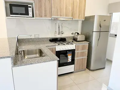 a kitchen with a sink and a stove and a refrigerator at HABITAT Departamentos in Villa Carlos Paz