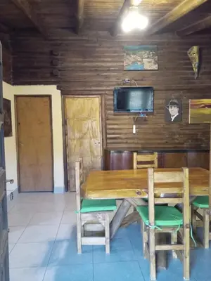 a dining room with a wooden table and chairs at Peumayen Cabañas in Villa de Las Rosas