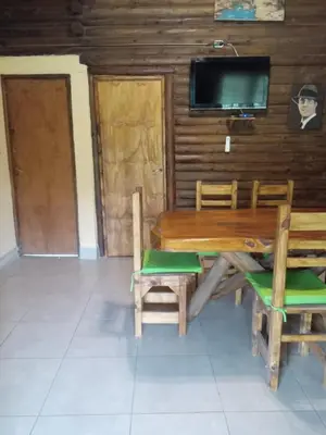 a dining room with a wooden table and chairs and a tv at Peumayen Cabañas in Villa de Las Rosas