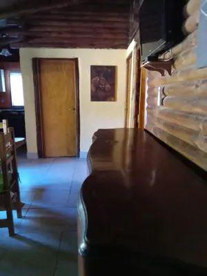 a dining room with a table and a wooden door at Peumayen Cabañas in Villa de Las Rosas
