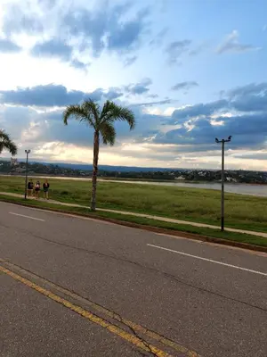 two people sitting on the side of a road with a palm tree at Castillo Del Lago - Carlos Paz - D16 in Villa Carlos Paz