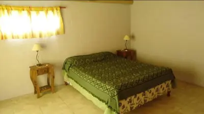 a bedroom with a green bed and two tables at Complejo Yarken in Potrero de Garay