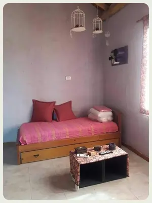 a bed with red pillows and a table in a room at Complejo Yarken in Potrero de Garay