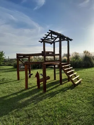a playground with a wooden structure in the grass at Complejo Yarken in Potrero de Garay