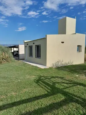 a white building with a grass field in front of it at Complejo Yarken in Potrero de Garay