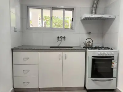 a white kitchen with a stove and a sink at Casa hasta 10 personas. in Villa Rumipal