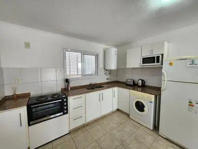 a kitchen with white cabinets and a washer and dryer at Depto La Leda in Almafuerte