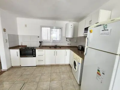 a kitchen with white cabinets and a white refrigerator at Depto La Leda in Almafuerte