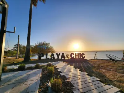a sign that reads playa chips with the sunset in the background at Depto La Leda in Almafuerte