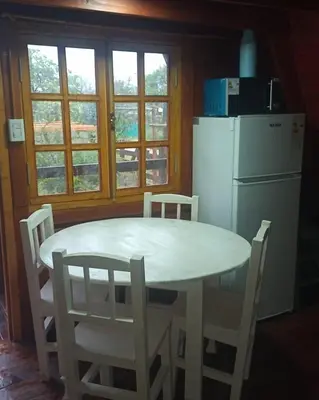 a kitchen with a white table and chairs and a refrigerator at CABAÑAS COPITL in Tanti