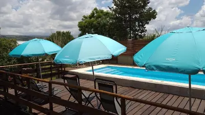 two blue umbrellas sitting next to a swimming pool at CABAÑAS COPITL in Tanti