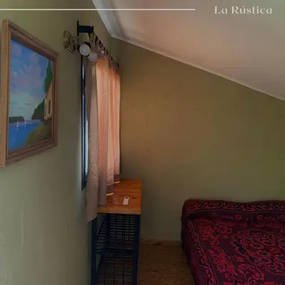 a bedroom with a bed and a table and a painting at La Rústica in La Bolsa