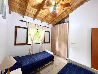 a bedroom with a blue bed and a ceiling fan at La Casita de Karen in Villa General Belgrano