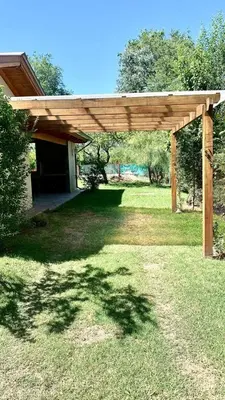 a wooden pergola in the middle of a yard at La Casita de Karen in Villa General Belgrano