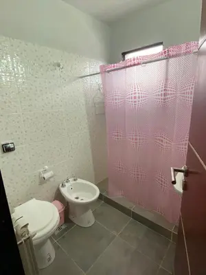 a bathroom with a toilet and a pink shower curtain at Departamento 2 dormitorios Villa Carlos Paz in Villa Carlos Paz
