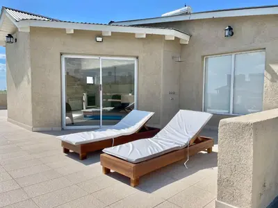 a patio with two beds on the side of a house at Cabaña con spa Vida Abundante in Villa Yacanto