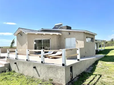 a house on a hill with a wooden deck at Cabaña con spa Vida Abundante in Villa Yacanto
