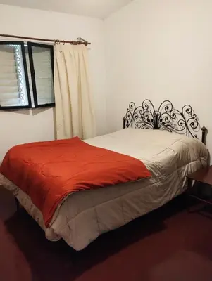 a bedroom with a bed with a red blanket and a window at Depto Cura Gaucho in Mina Clavero