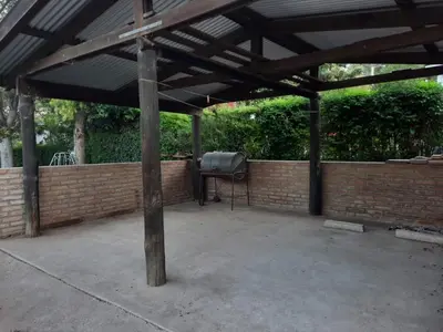 a covered patio with a grill and a brick wall at La Cabañita in Villa General Belgrano