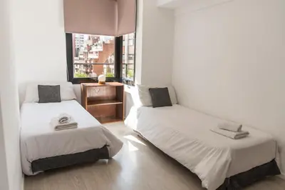 two beds in a room with a window at Babel Nueva Córdoba in Cordoba