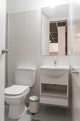 a white bathroom with a toilet and a sink at Babel Nueva Córdoba in Cordoba