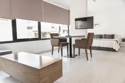 a living room with a table and chairs and a bed at Babel Nueva Córdoba in Cordoba