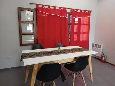 a table and chairs in a room with a red curtain at Dpto Santa Rosa in Santa Rosa de Calamuchita