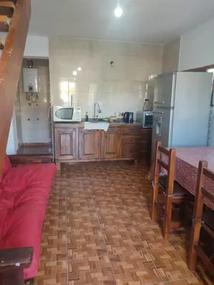 a kitchen with wooden cabinets and a refrigerator and a table at Cabañas Los Materos in Santa María