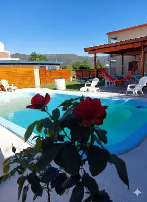 a plant with red roses next to a swimming pool at Cabañas Los Materos in Santa María