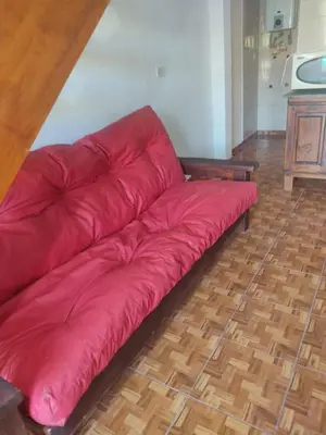 a red leather couch sitting on a wooden floor at Cabañas Los Materos in Santa María