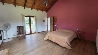 a bedroom with a bed in a red wall at Atardecida in Villa de Las Rosas