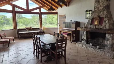 a dining room with a table and a fireplace at Atardecida in Villa de Las Rosas