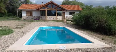 a swimming pool in front of a house at Atardecida in Villa de Las Rosas