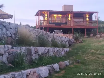 a house with a stone wall in front of it at Cabaña LA PEDRERA - Pileta y a metros del Rio in Bialet Massé