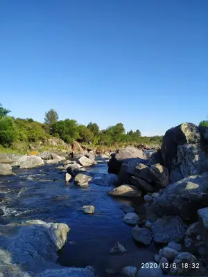 a river with rocks and trees in the background at Cabaña LA PEDRERA - Pileta y a metros del Rio in Bialet Massé
