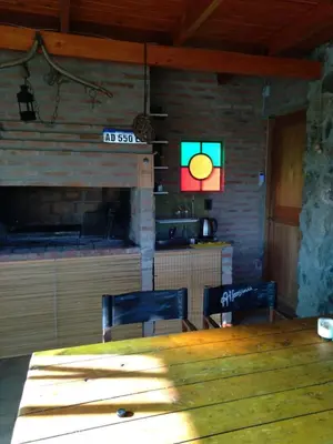 a dining room with a table and chairs and a clock at Cabaña LA PEDRERA - Pileta y a metros del Rio in Bialet Massé