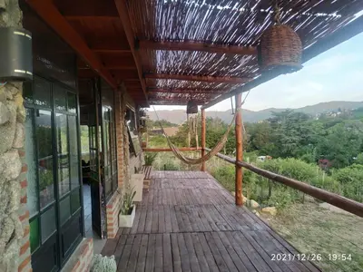 a porch of a house with a wooden deck at Cabaña LA PEDRERA - Pileta y a metros del Rio in Bialet Massé