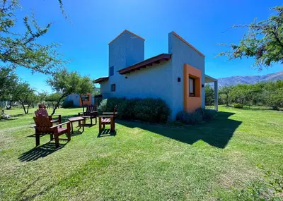 a person sitting at a table in front of a house at Complejo La Dorada in Merlo