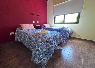 two beds in a room with red walls at Complejo La Dorada in Merlo
