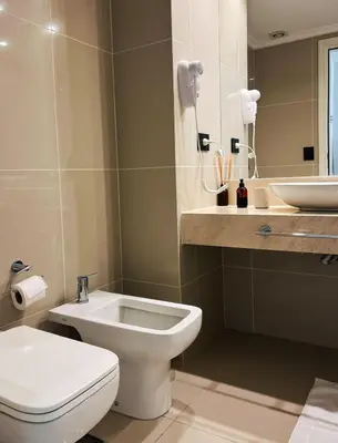 a bathroom with a white toilet and a sink at Apart France - Un dormitorio con gim, piscina y estacionamiento in Río Cuarto