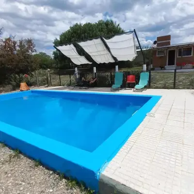 a large blue swimming pool with two chairs next to it at cabañas fátima in Villa de Las Rosas