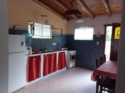 a kitchen with white appliances and red towels on the counters at cabañas fátima in Villa de Las Rosas